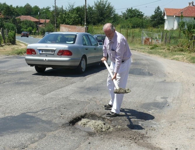 Не е за вярване! Депутат хвана лопатата и запълни огромна дупка на пътя СНИМКА