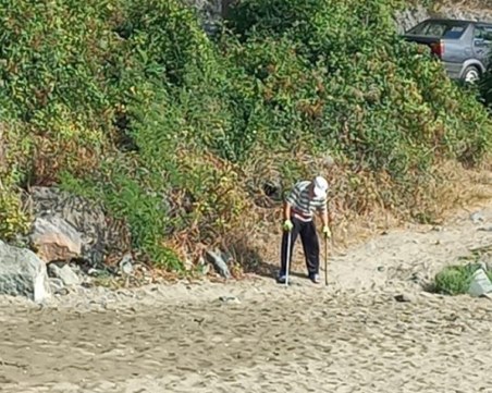 85-годишен мъж с два бастуна почиства фасовете на туристите от плажа